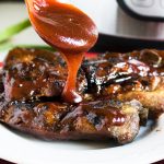 rib tips with BBQ sauce on a plate with a spoon drizzling on BBQ sauce