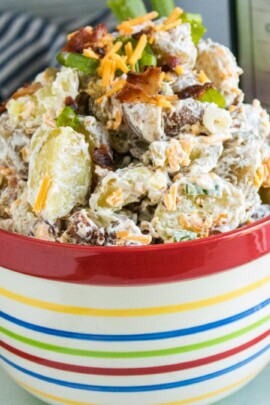 loaded baked potato salad in a tall rainbow striped bowl