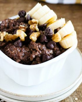 chocolate banana bread with banana slices on top in a white square bowl