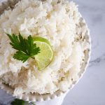 cooked rice in a bowl with a lime on top