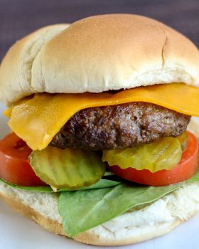 hamburger with cheese, lettuce, tomato, and pickles