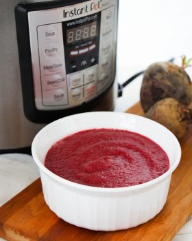instant pot beet soup in a white bowl on a wood cutting board