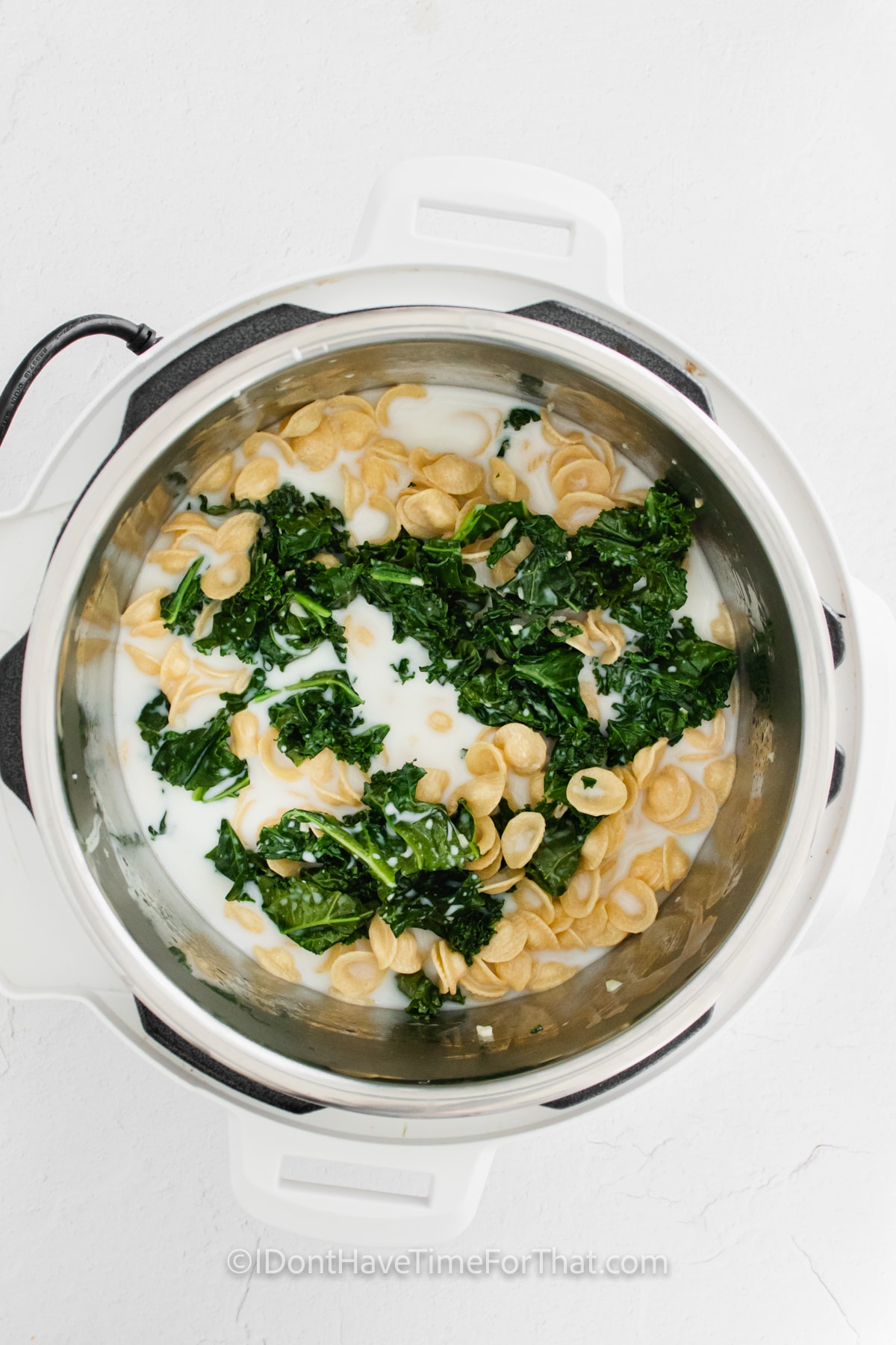adding pasta and cream to make Instant Pot Orecchiette with Kale