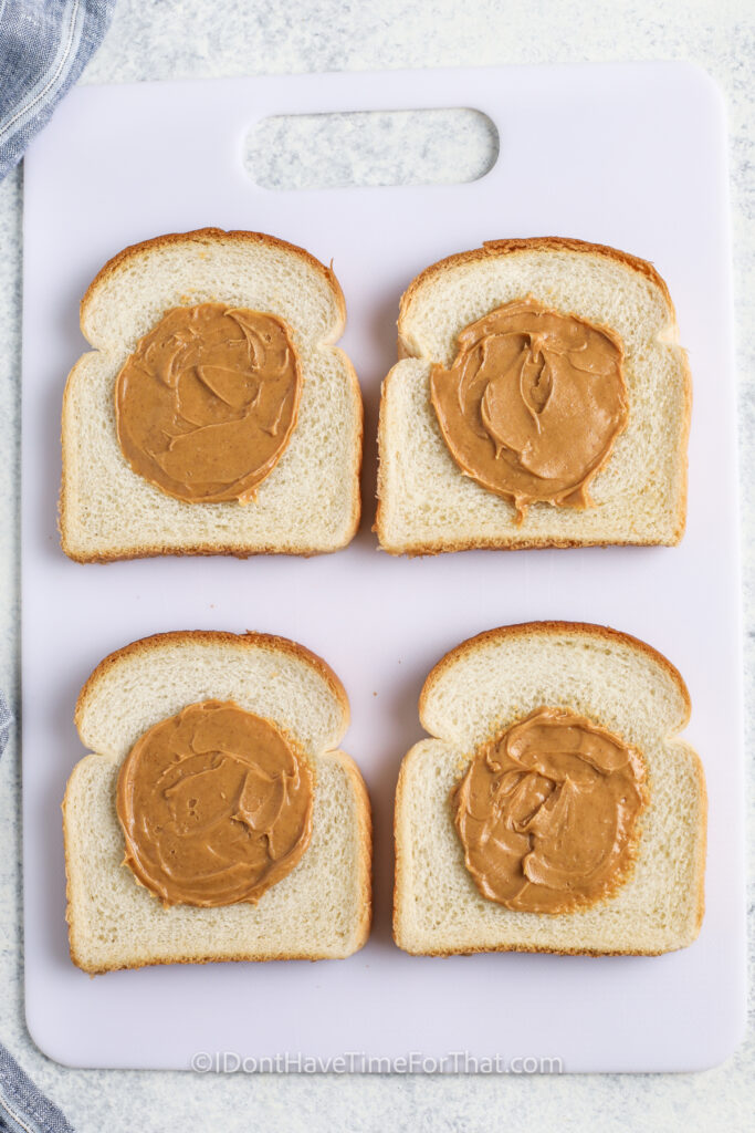 adding peanut butter to bread to make Homemade Uncrustables