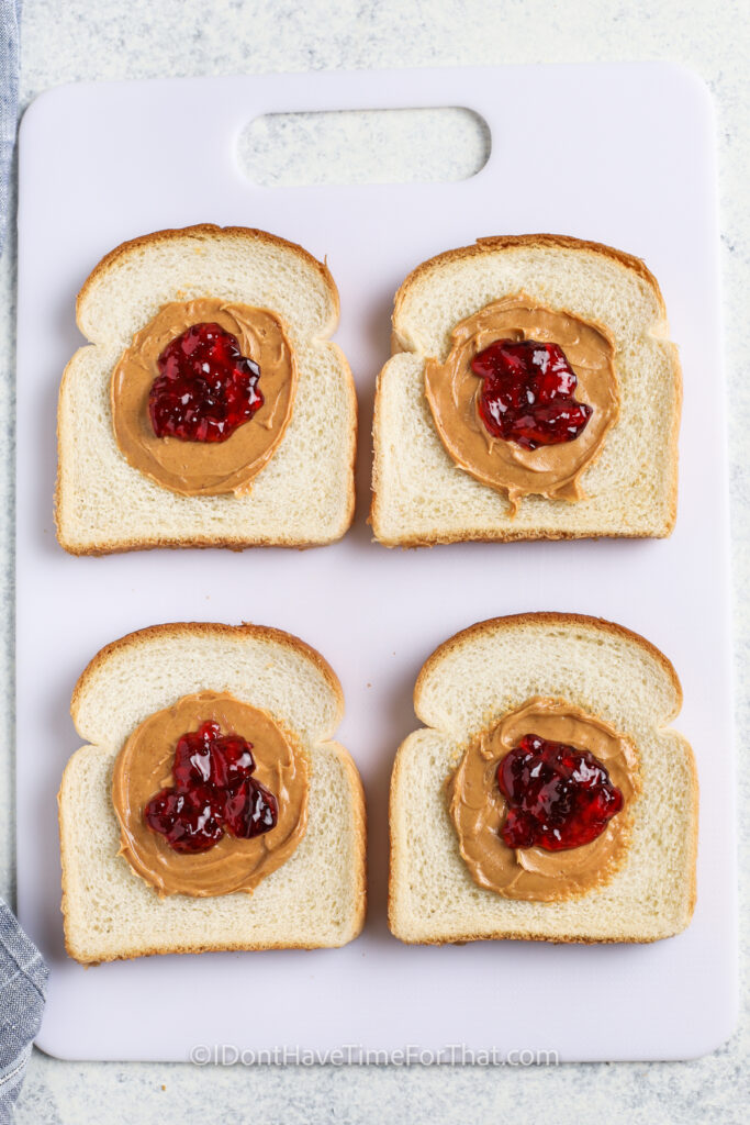 adding jelly to bread to make Homemade Uncrustables
